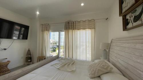 een witte slaapkamer met een groot bed en een raam bij The Cove - Location is everything! - Luxurious - Free parking in Palm-Eagle Beach