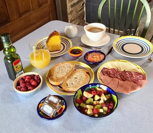 a table with plates of food and bread and drinks at Casa Rural Dana in Castelo