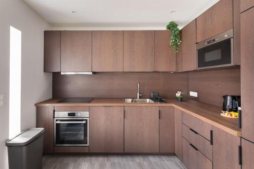une cuisine avec des armoires en bois, un évier et une cuisinière dans l'établissement Maison moderne avec jardin12 pers proche Paris & Disney, à Neuilly-sur-Marne