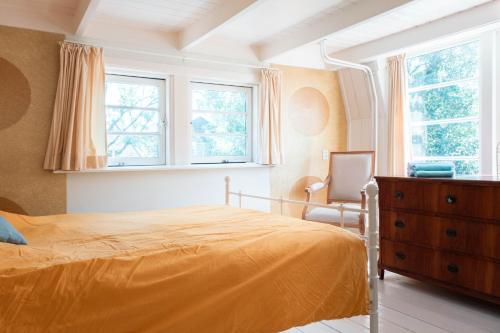een slaapkamer met een bed, een dressoir en ramen bij Bed and breakfast Jan in Edam
