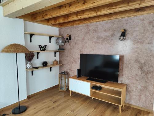 a living room with a flat screen tv on a wall at la maisonnette in Saignelégier