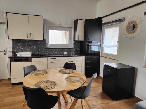 cocina con mesa de madera y sillas en la maisonette, en Saignelégier