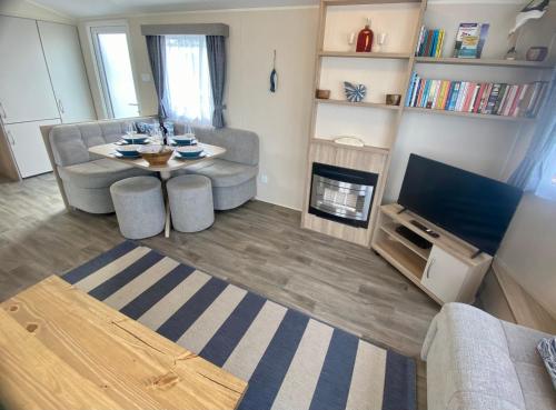 a living room with a couch and a table and a tv at Gannets Rest - Spacious Static Caravan with Sea Views in Polperro