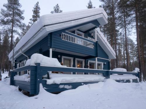 Ein blaues Haus im Schnee im Wald in der Unterkunft Villa Vilttitossu in Äkäslompolo