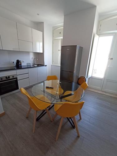 a kitchen with a glass table and yellow chairs at FAMILY APARTAMENT II in Coimbra