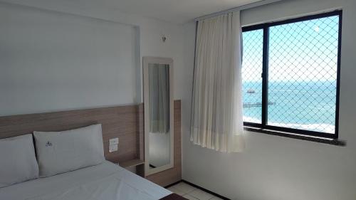 a bedroom with a bed and a large window at Vista espetacular 4 pessoas Praia de Iracema in Fortaleza