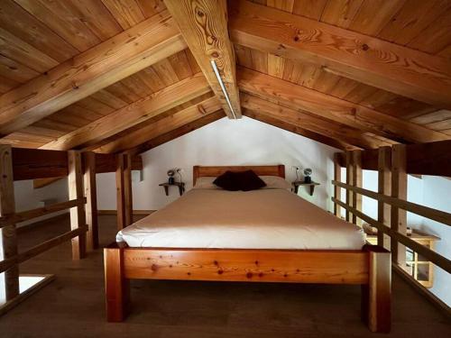 Cama grande en habitación con techo de madera en Il nido al Maso Maoro, en Sant’Orsola