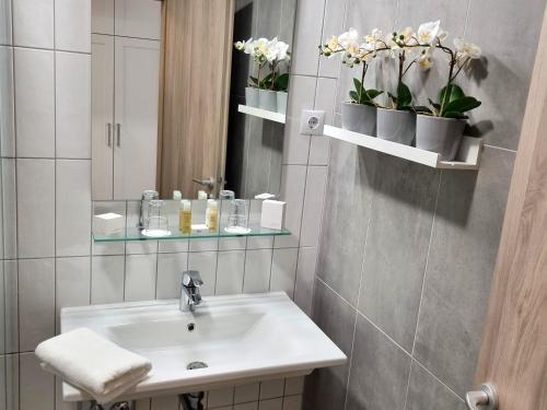 bagno con lavandino, specchio e fiori di Baross40 Apartments a Budapest
