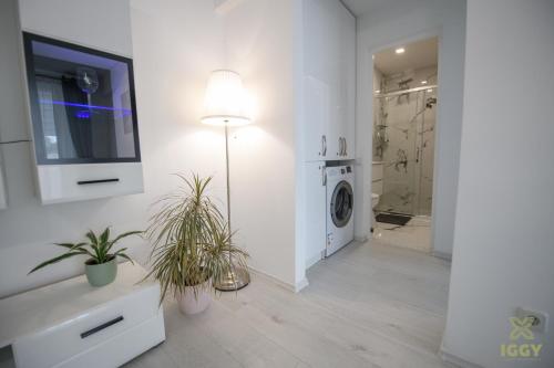 bagno bianco con TV e lavatrice di Iggy Luxury Central Apartment a Hunedoara