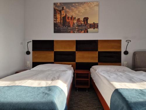 a room with two beds and a painting on the wall at Hotel Podróżnik in Koszuty