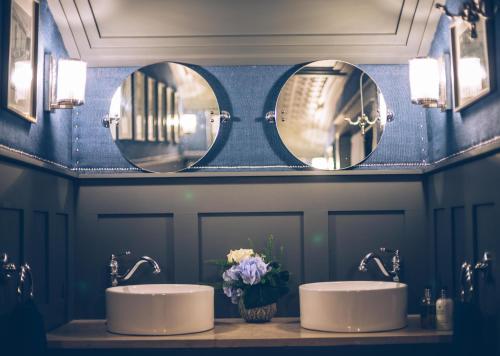 two sinks in a bathroom with two mirrors at Sheddington Manor - 2 Bedroom Guest House & Cinema in Belfast