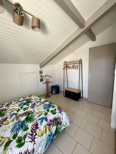 une chambre avec un lit avec une couette fleurie dans l'établissement La Villa Louca - Charme, Soleil & Détente aux Portes des Landes, à Saint-Vincent-de-Tyrosse