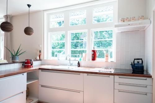 una cocina blanca con armarios blancos y ventanas en Bed and breakfast Jan, en Edam