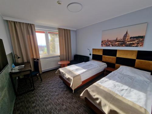 een hotelkamer met 2 bedden en een bureau bij Hotel Podróżnik in Koszuty