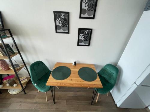 a wooden table with green chairs in a room at 1-izbový byt in Košice