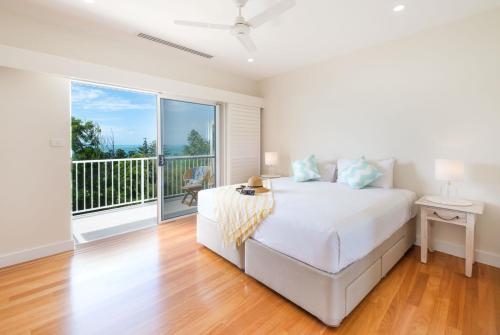 a white bedroom with a bed and a balcony at La Bella Waters 3 - Oceanview's, Pool, Buggy and Transfers in Hamilton Island