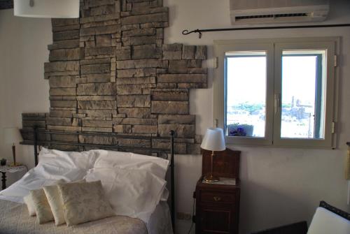 a bedroom with a brick wall and a bed and a window at Casa tipica siciliana patronale home BedandBreakfast TreMetriSoprailCielo Camere con vista, colazione interna in terrazzo panoramico in Caltagirone