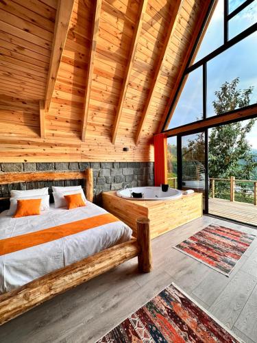 Dormitorio en cabaña de madera con cama y bañera en Şeni Bungalow en Çamlıhemşin