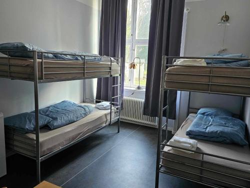 a room with three bunk beds and a window at Stora Ekeberg vandrarhem in Axvall