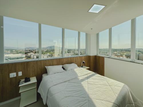 a bedroom with a large bed and large windows at Go Inn Aracruz in Aracruz