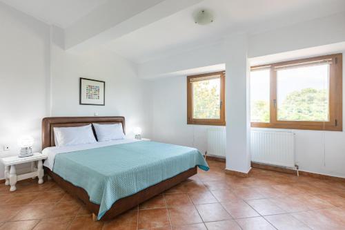 a bedroom with a bed with a green blanket and two windows at The Olympus Garden Beach House in Litochoro