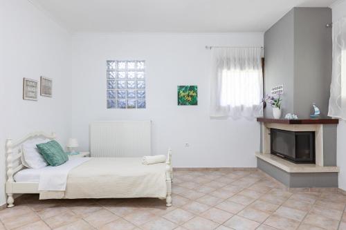 a white bedroom with a bed and a fireplace at The Olympus Garden Beach House in Litochoro