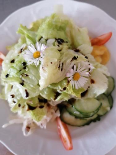 a white plate with a salad with flowers on it at Alpengasthof Fernblick in Mönichkirchen