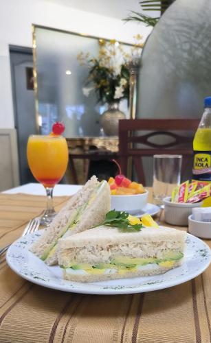 a sandwich on a plate on a table with a glass of orange juice at Faraona Grand Hotel in Lima