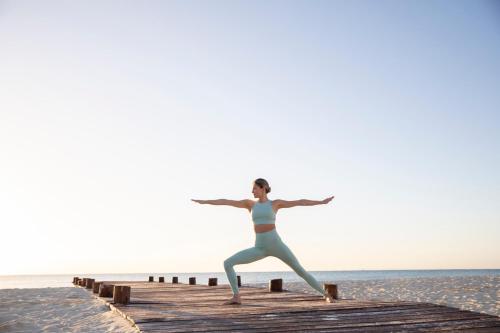 a woman doing yoga on a pier near the ocean at Hyatt Zilara Riviera Maya Adults Only All-Inclusive in Playa del Carmen