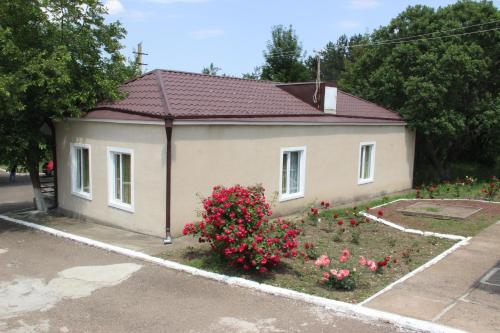 une petite maison avec des fleurs roses dans une cour dans l'établissement Hotel Lori Berd, à Stepanavan