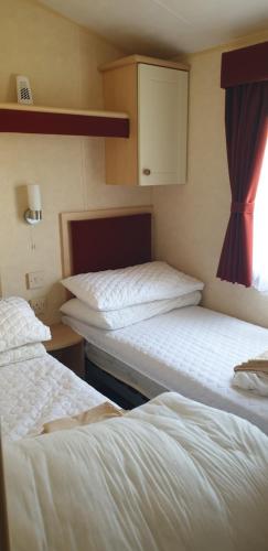 two beds sitting next to each other in a room at 2 bed pet friendly caravan at Hoburne Devon Bay with decking in Paignton