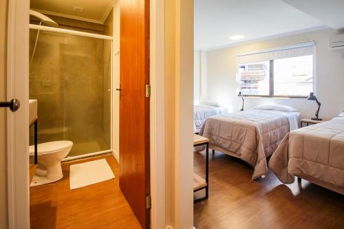 a small room with two beds and a bathroom at Pousada Blumenau in Blumenau