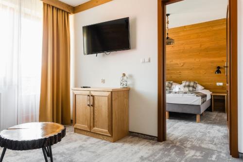 a hotel room with a bed and a television on the wall at Leśne Apartamenty in Białka Tatrzanska