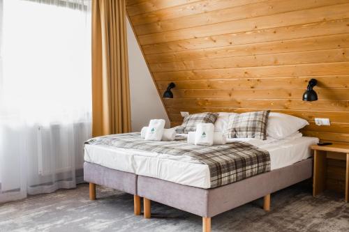 a bedroom with a bed with a wooden wall at Leśne Apartamenty in Białka Tatrzanska
