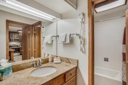 W łazience znajduje się umywalka, wanna i lustro. w obiekcie Laurelwood Condominiums 302 w mieście Snowmass Village