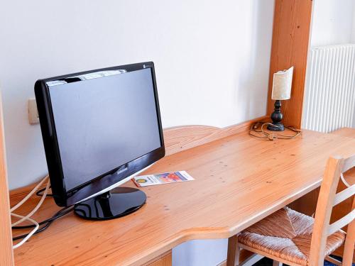 monitor komputerowy siedzący na drewnianym biurku w obiekcie Hotel Ristorante La Baitina w mieście Asiago