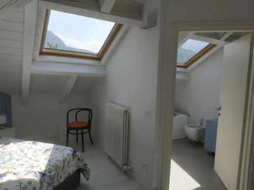 1 dormitorio con cama, ventana y silla en Deliziosa mansarda en Trento