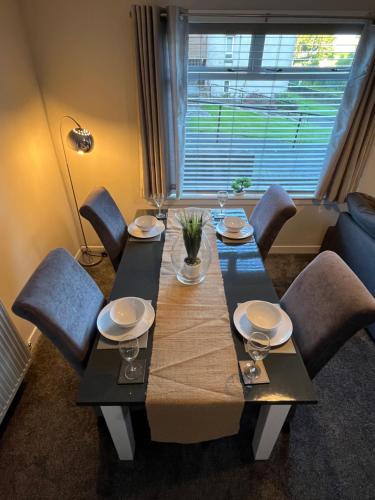 a dining room table with chairs and a large window at Erskine Apartment in Erskine