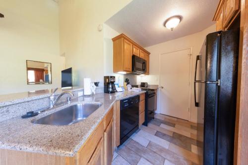 a kitchen with a sink and a black refrigerator at Makai Club Resort in Princeville