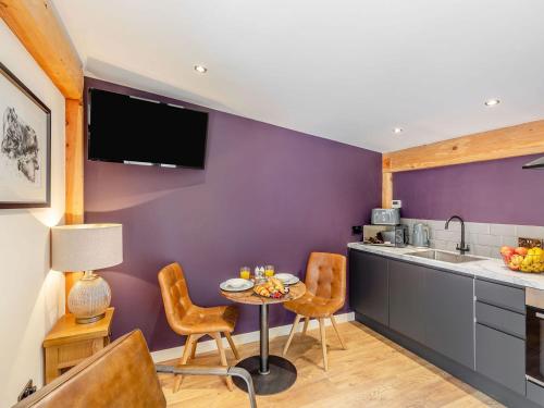 a kitchen with purple walls and a table and chairs at Daffodil - Uk40266 in Llangadfan