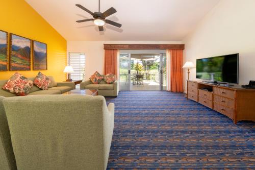 a living room with two couches and a flat screen tv at Makai Club Resort in Princeville