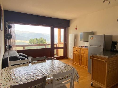 uma cozinha com uma mesa e uma grande janela em Le Cantou - cocon chaleureux em Font Romeu Odeillo Via