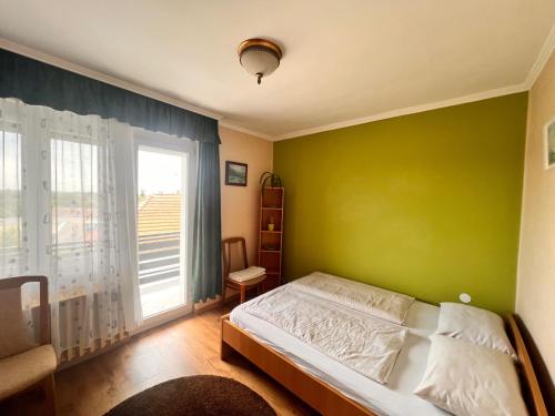 um quarto com uma cama e uma parede verde em Bem Apartman em Gyenesdiás