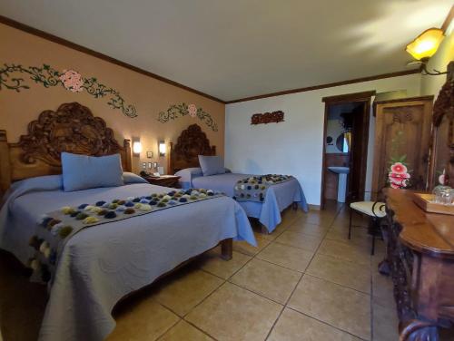 a bedroom with two beds and a table and a desk at Hotel Grand Maria in San Cristóbal de Las Casas
