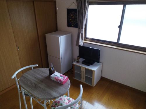 a small room with a table and a refrigerator at IIIハウス　ひらパーからすぐの３階建て一軒家　全寝室エアコン新調　wifi完備　旅行&ビジネス大歓迎 in Hirakata