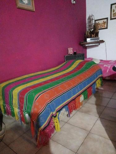 Cama en habitación con pared de color rosa en Hostel Monte Grande en Monte Grande