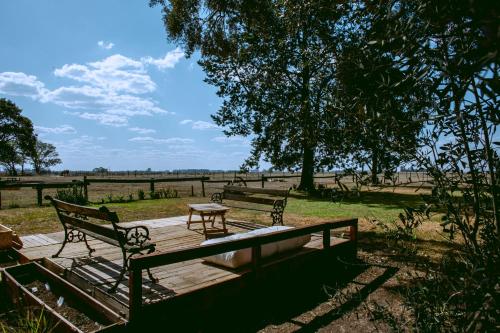 two benches and a table on a wooden deck at Inti, hospedaje de campo. in Bartolomé Mitre