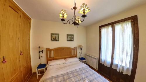 Un dormitorio con una cama grande y una lámpara de araña. en Los Avellanos de Escarrilla - tucasaenlospirineos, en Escarrilla