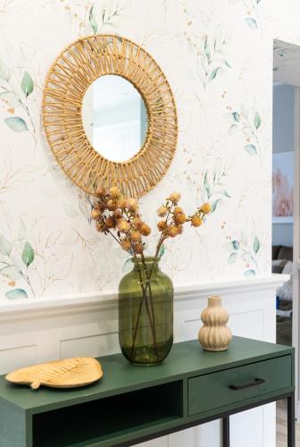 a mirror and a vase with flowers on a table at Alfama Garden in Grudziądz