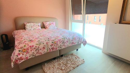 een slaapkamer met een bed met een roze dekbed en een raam bij Mooi vakantiehuis tussen Breda, Antwerpen, Gent & Hasselt in Antwerpen